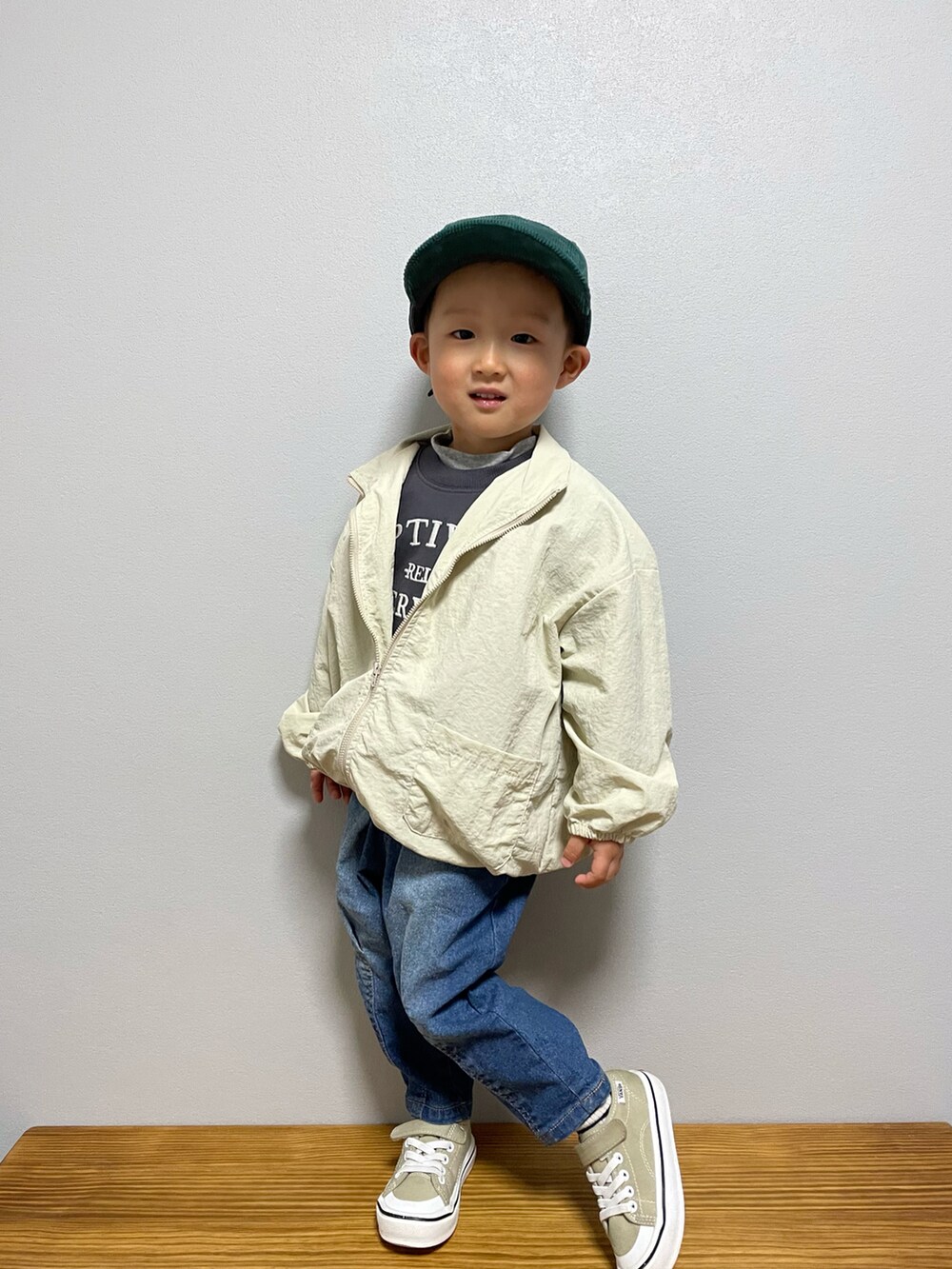 ベージュ系のナイロンジャケット、ホワイト系のTシャツ/カットソー、ブルー系のデニムパンツを着用したキッズの春コーディネートの3枚目の写真