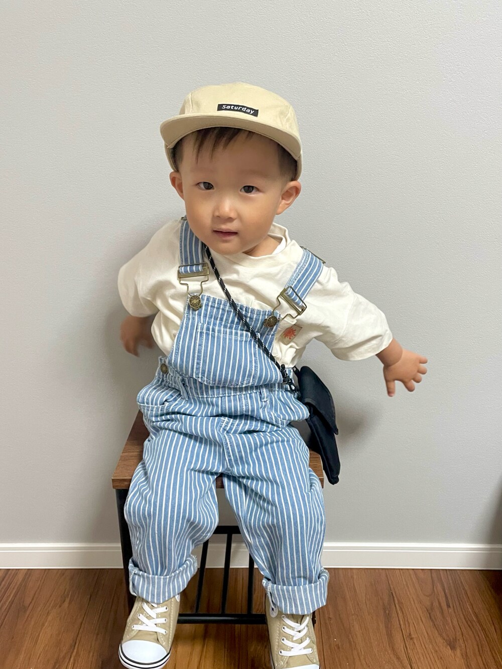 ブラック系のショルダーバッグ、ホワイト系のTシャツ/カットソー、ブルー系のサロペット/オーバーオールを着用したキッズの春コーディネートの2枚目の写真