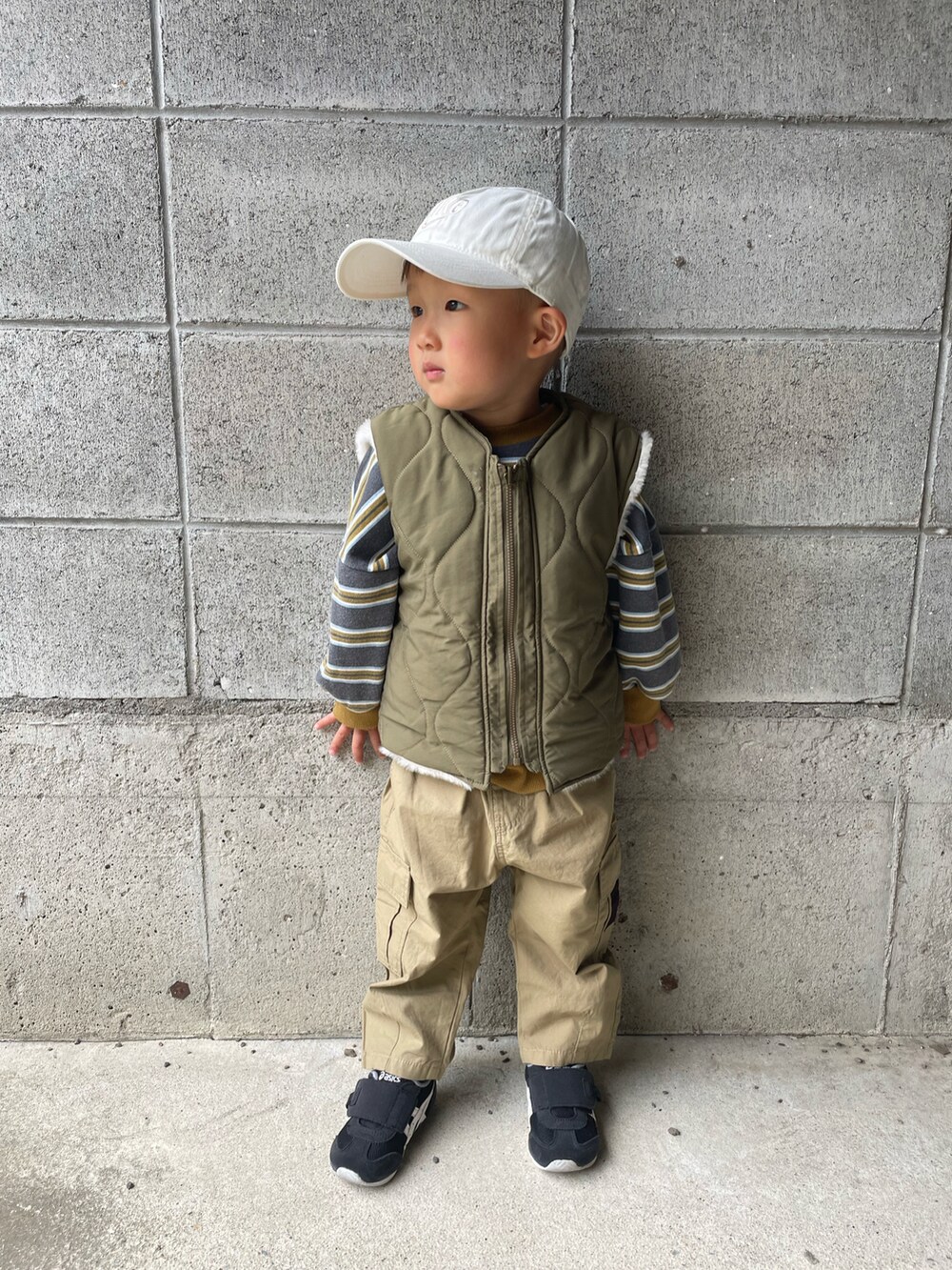 グリーン系のダウンベスト、グレー系のスウェット、ベージュ系のカーゴパンツを着用したキッズの春コーディネートの2枚目の写真