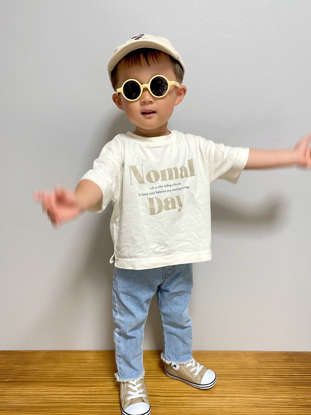 ベージュ系のTシャツ/カットソー、ベージュ系のスニーカー、ブルー系のデニムパンツを着用したキッズの春コーディネートの3枚目の写真