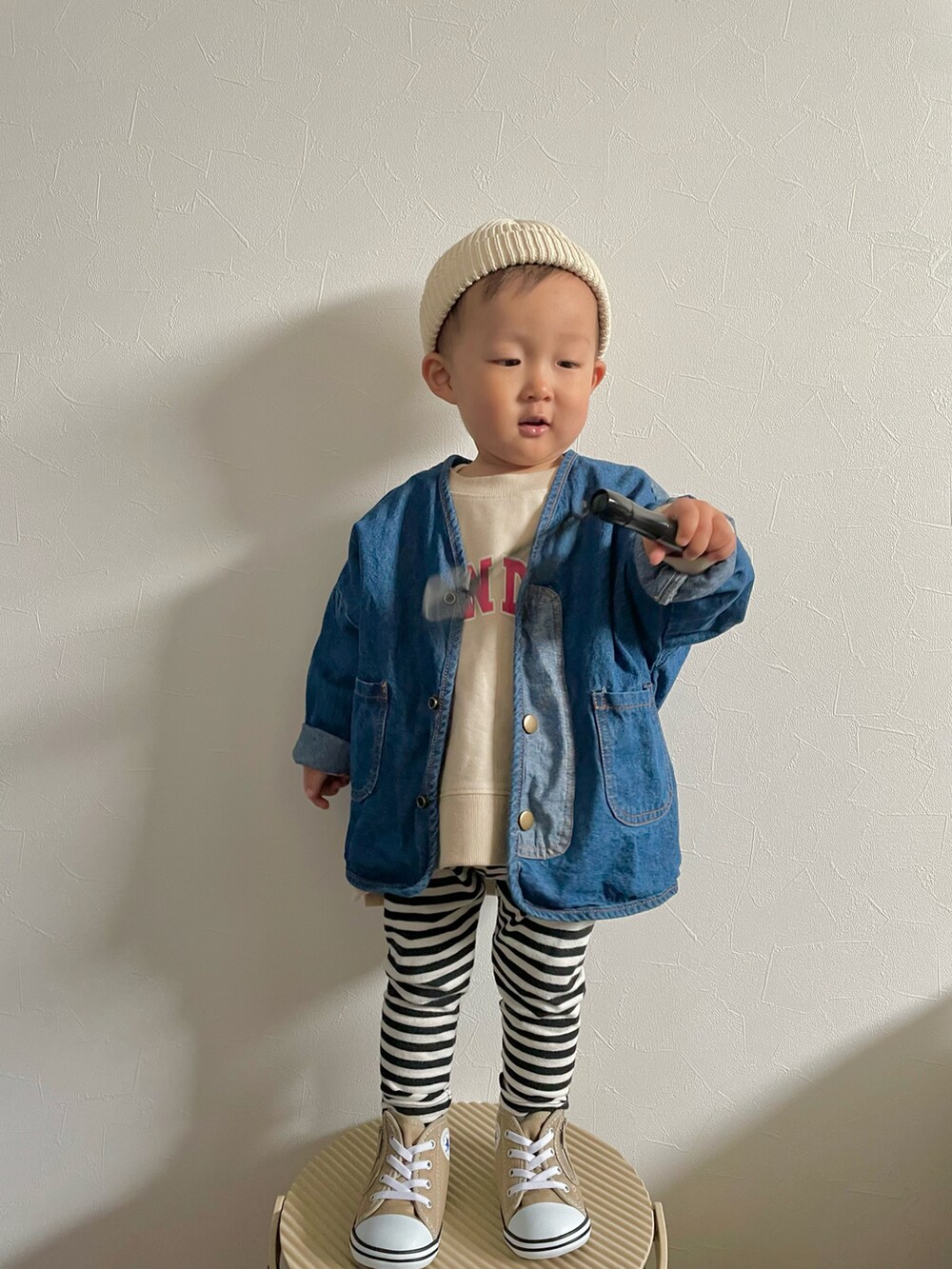 ベージュ系のスウェット、ブルー系のデニムジャケット、ベージュ系のスニーカーを着用したキッズの春コーディネートの2枚目の写真