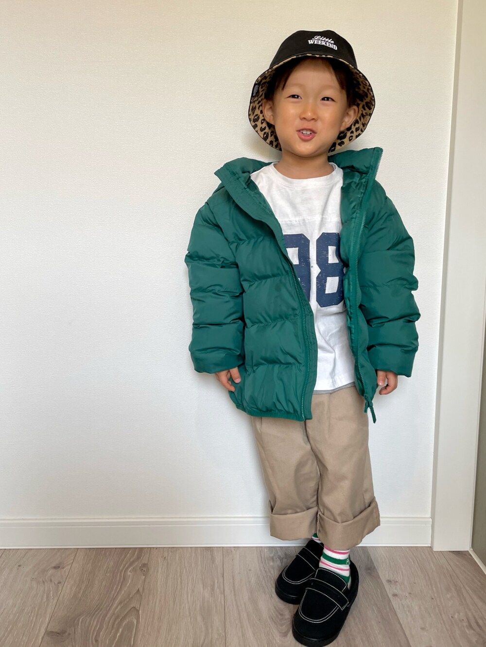 ホワイト系のTシャツ/カットソー、グリーン系のダウンジャケット/コート、ベージュ系のチノパンツを着用したキッズの冬コーディネートの4枚目の写真