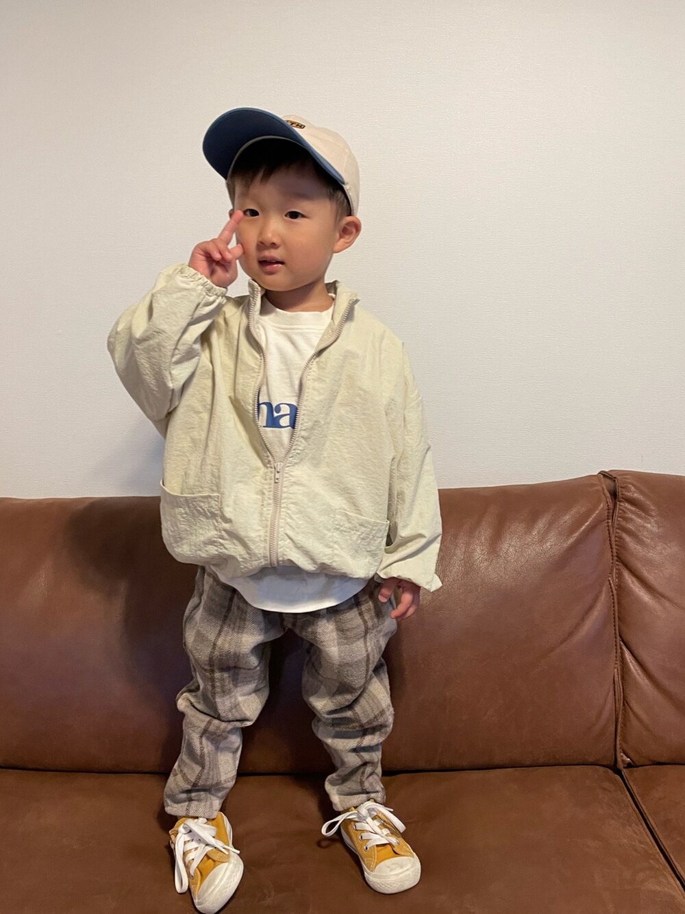 ベージュ系のナイロンジャケット、ホワイト系のTシャツ/カットソー、イエロー系のスニーカーを着用したキッズの春コーディネートの3枚目の写真