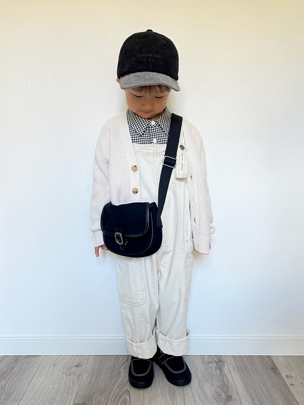 ブラック系のシャツ/ブラウス、ブラック系のショルダーバッグ、ホワイト系のカーディガン/ボレロを着用したキッズの冬コーディネートの3枚目の写真