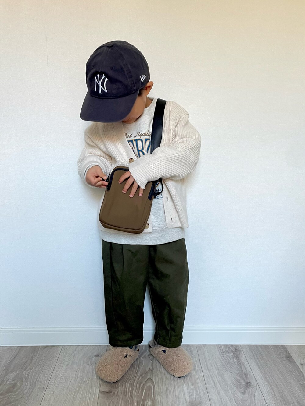 グレー系のスウェット、ブラウン系のショルダーバッグ、ホワイト系のカーディガン/ボレロを着用したキッズの冬コーディネートの3枚目の写真