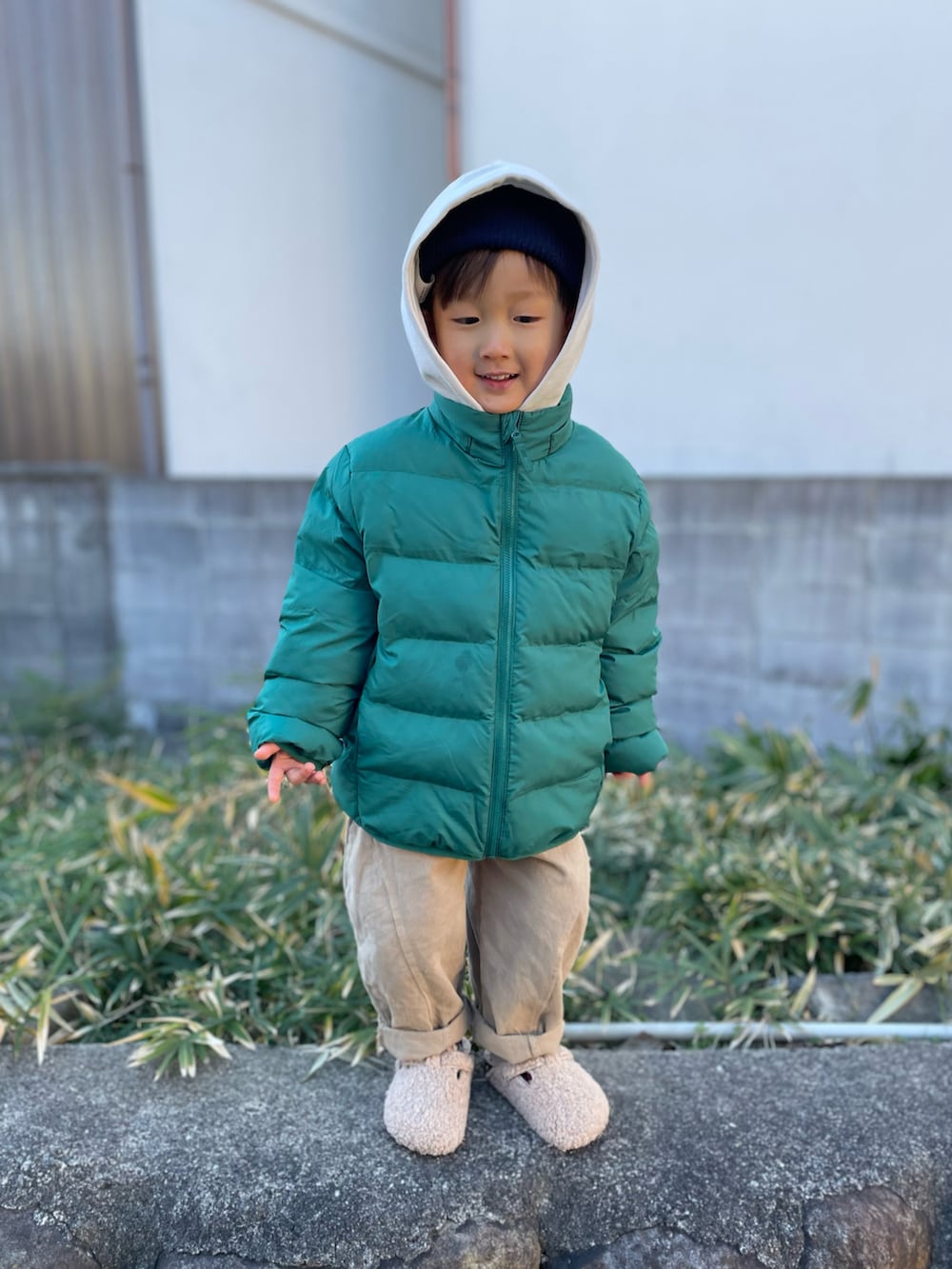 グリーン系のダウンジャケット/コート、ホワイト系のパーカー、ベージュ系のパンツを着用したキッズの冬コーディネートの2枚目の写真