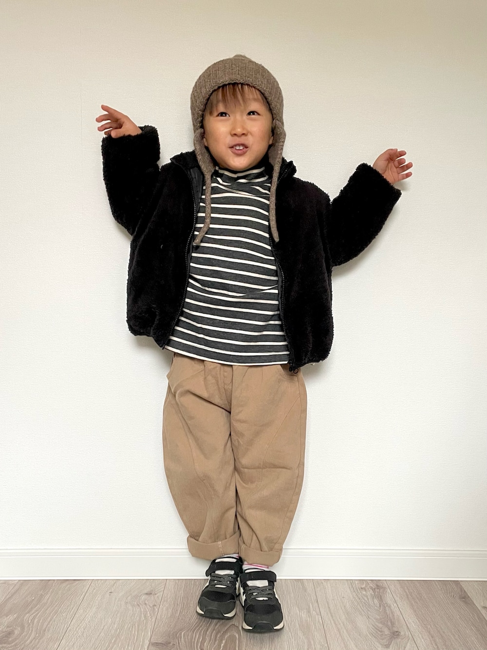 ブラック系のTシャツ/カットソー、ベージュ系のパンツ、ブラック系のスニーカーを着用したキッズの冬コーディネートの4枚目の写真