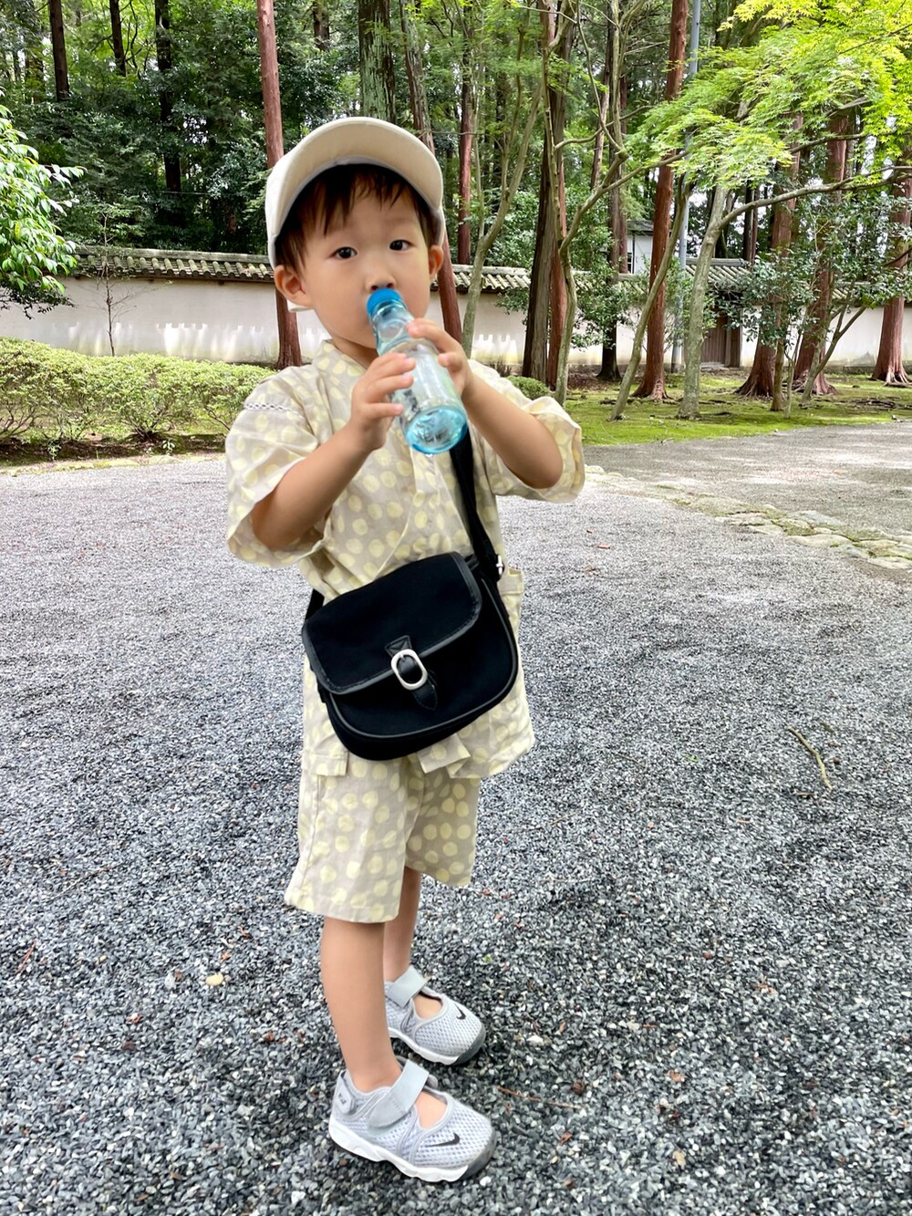 ブラック系のショルダーバッグ、グレー系のスニーカー、ブラウン系のハットを着用したキッズの夏コーディネートの3枚目の写真
