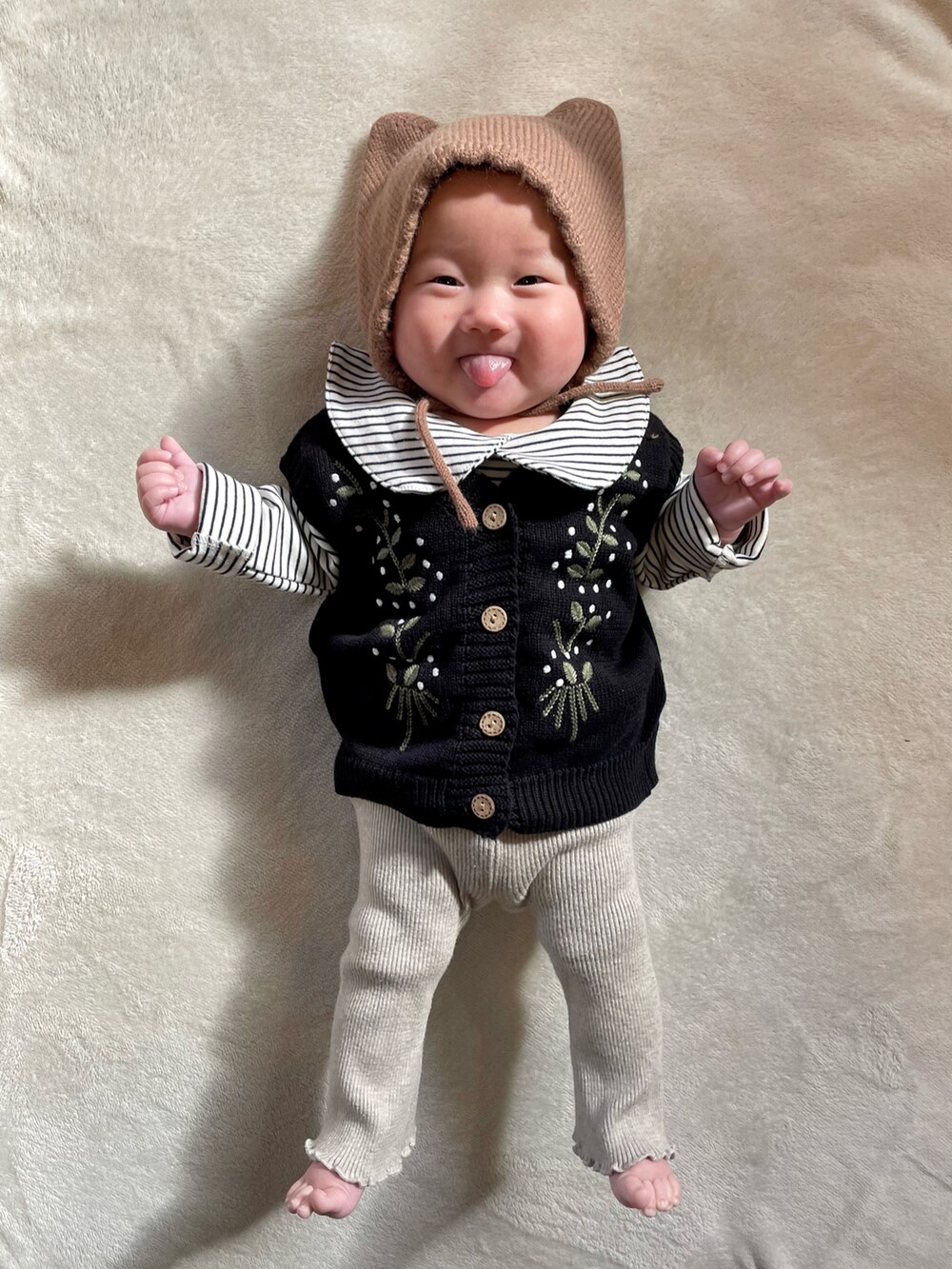 ブラック系のベスト、ベージュ系のセットアップ、ブラウン系のヘアバンドを着用したキッズの冬コーディネートの3枚目の写真