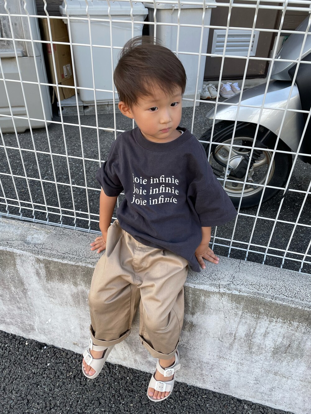 グレー系のTシャツ/カットソー、ベージュ系のチノパンツ、ベージュ系のサンダルを着用したキッズの夏コーディネートの4枚目の写真