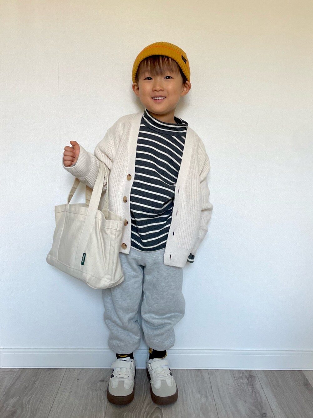 ブラック系のTシャツ/カットソー、ホワイト系のカーディガン/ボレロ、グレー系のスウェットパンツを着用したキッズの冬コーディネートの2枚目の写真