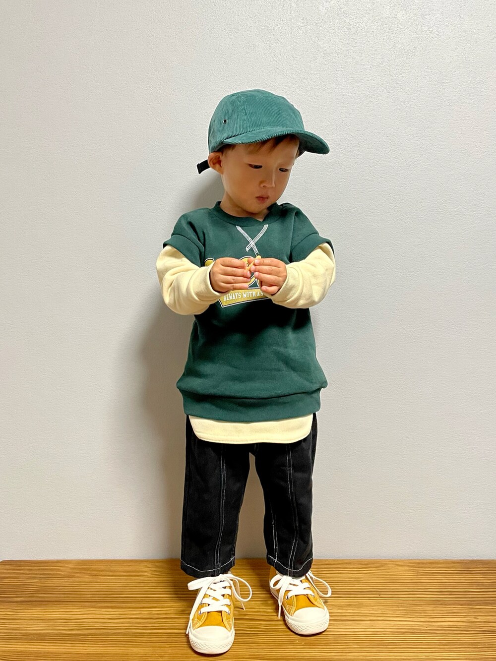 グリーン系のスウェット、ブラック系のパンツ、イエロー系のスニーカーを着用したキッズの秋コーディネートの2枚目の写真