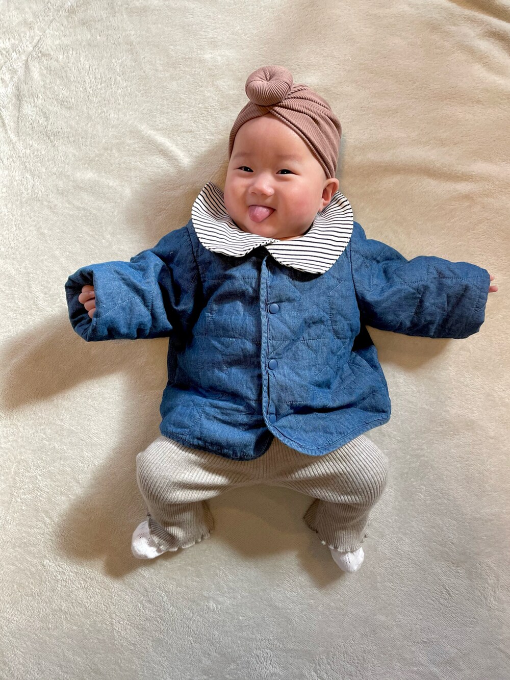 ブルー系のノーカラージャケット、ベージュ系のセットアップ、ブラック系のロンパースを着用したキッズの冬コーディネートの4枚目の写真