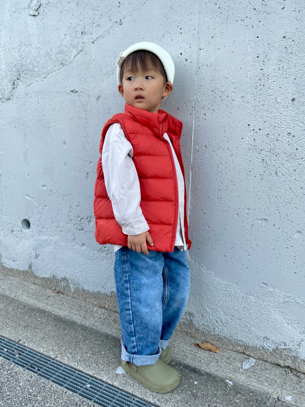 ベージュ系のシャツ/ブラウス、オレンジ系のダウンベスト、ブルー系のデニムパンツを着用したキッズの秋コーディネートの3枚目の写真