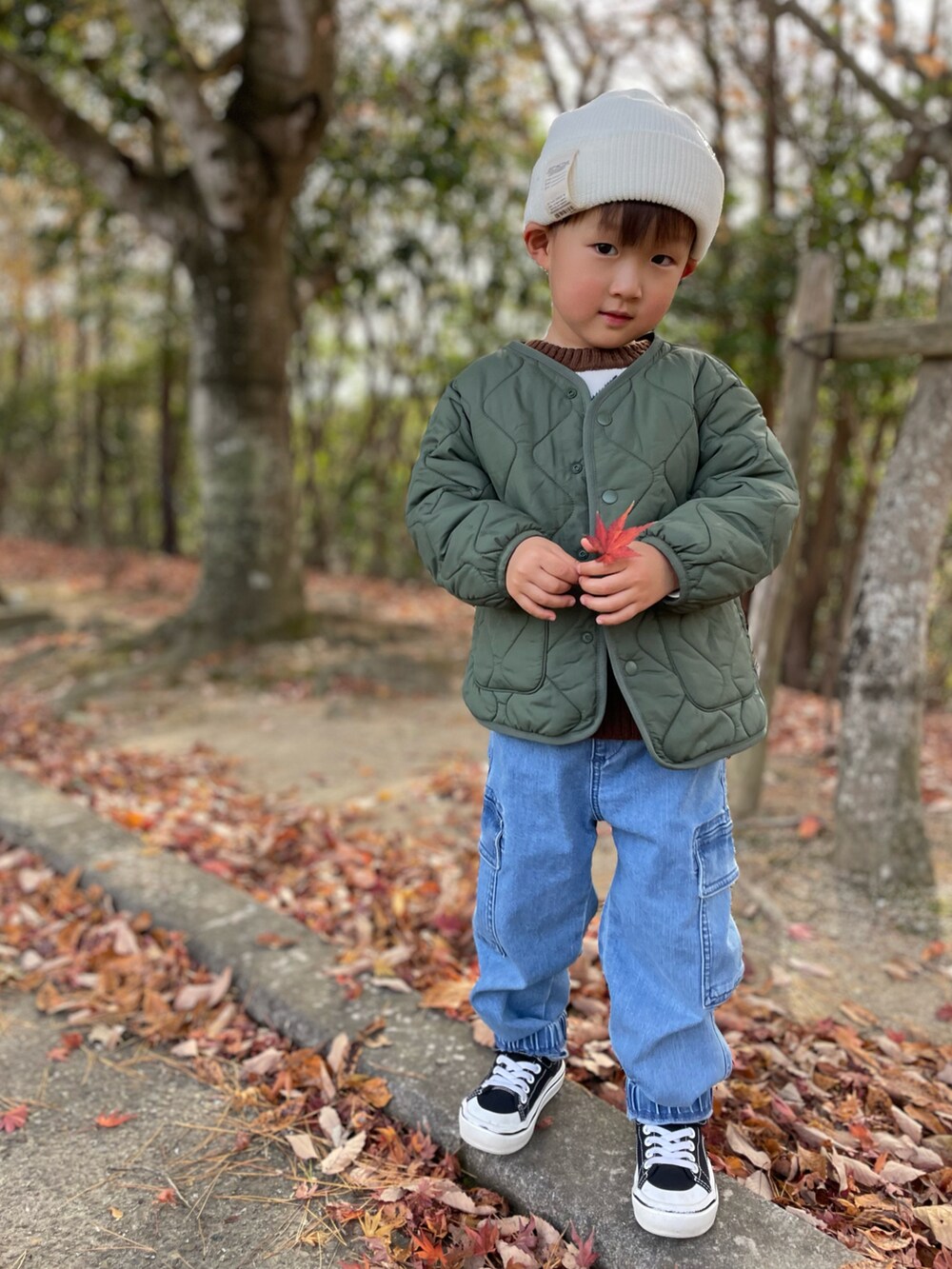 ブラウン系のニット/セーター、グリーン系のノーカラージャケット、ブルー系のカーゴパンツを着用したキッズの冬コーディネートの4枚目の写真