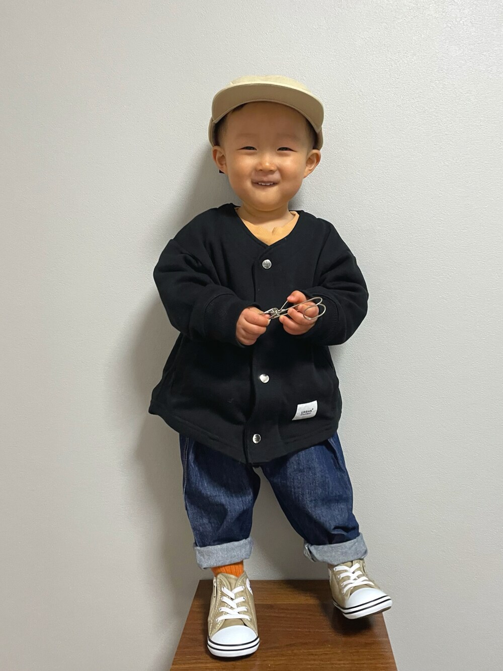 ブラック系のノーカラージャケット、オレンジ系のスウェット、その他のデニムパンツを着用したキッズの冬コーディネートの3枚目の写真