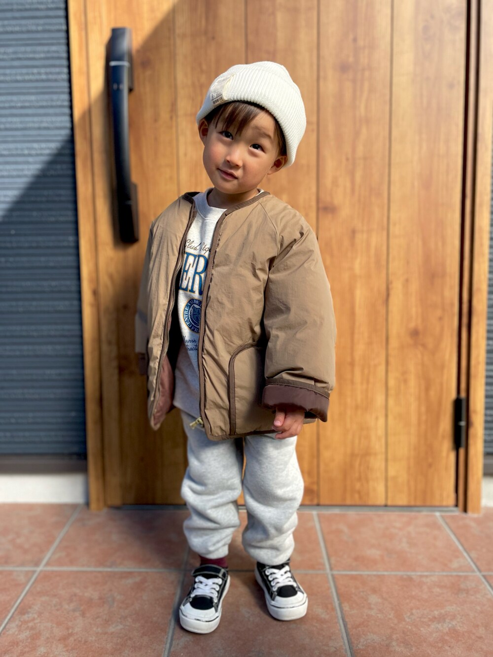 グレー系のスウェット、ブラウン系のノーカラージャケット、グレー系のスウェットパンツを着用したキッズの冬コーディネートの3枚目の写真