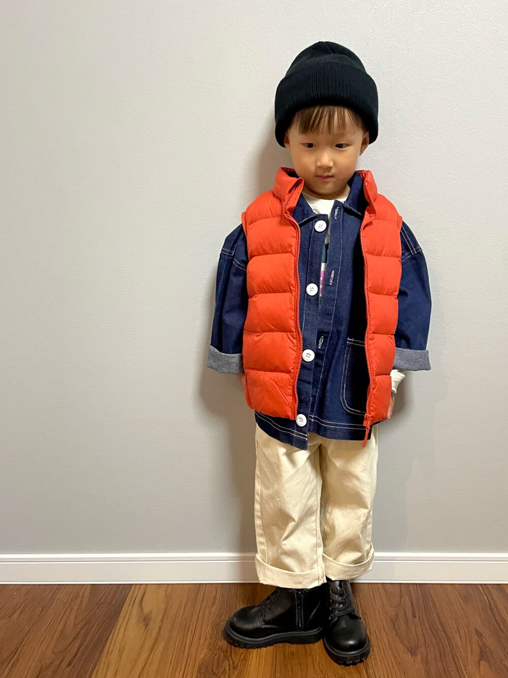 オレンジ系のダウンベスト、ブルー系のデニムジャケット、ホワイト系のデニムパンツを着用したキッズの秋コーディネートの2枚目の写真