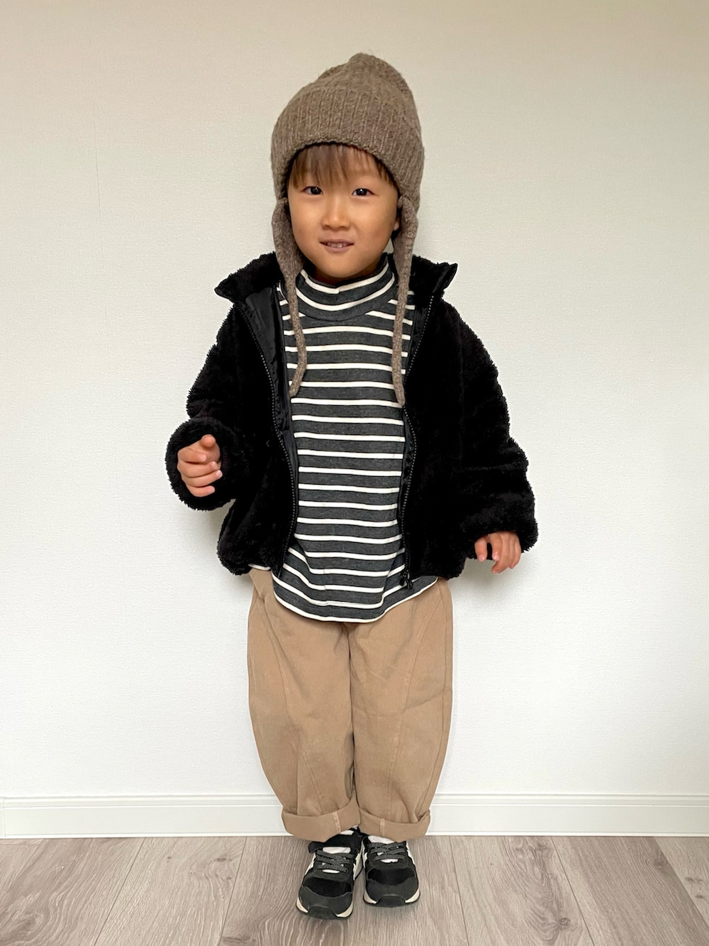 ブラック系のTシャツ/カットソー、ベージュ系のパンツ、ブラック系のスニーカーを着用したキッズの冬コーディネートの2枚目の写真