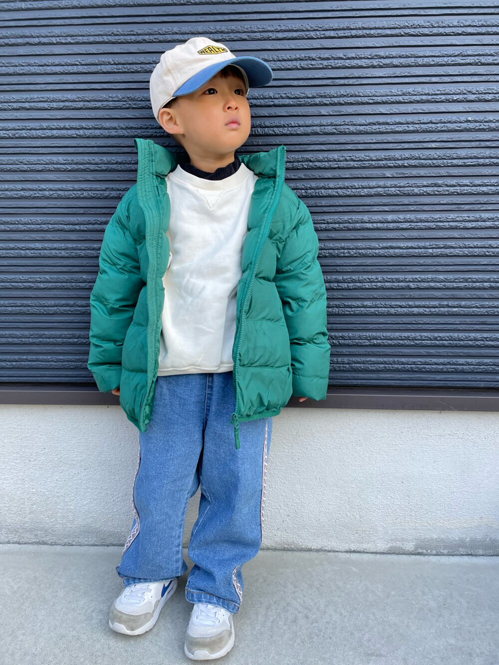 ホワイト系のスウェット、グリーン系のダウンジャケット/コート、ブルー系のデニムパンツを着用したキッズの冬コーディネートの2枚目の写真