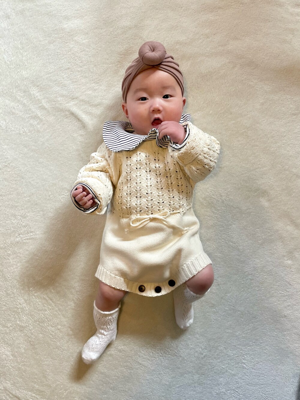 ブラウン系のヘアバンド、ブラック系のロンパース、ホワイト系のロンパースを着用したキッズの冬コーディネートの5枚目の写真