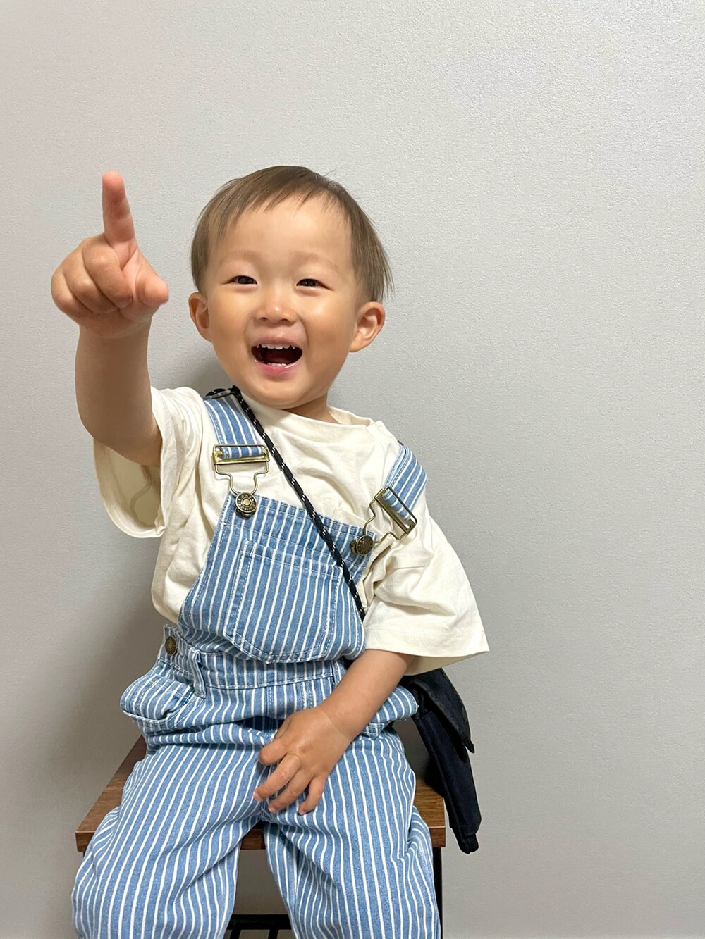 ブラック系のショルダーバッグ、ホワイト系のTシャツ/カットソー、ブルー系のサロペット/オーバーオールを着用したキッズの春コーディネートの5枚目の写真