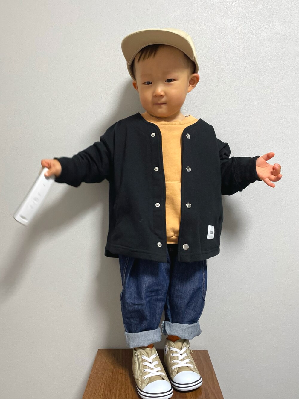 ブラック系のノーカラージャケット、オレンジ系のスウェット、その他のデニムパンツを着用したキッズの冬コーディネートの5枚目の写真