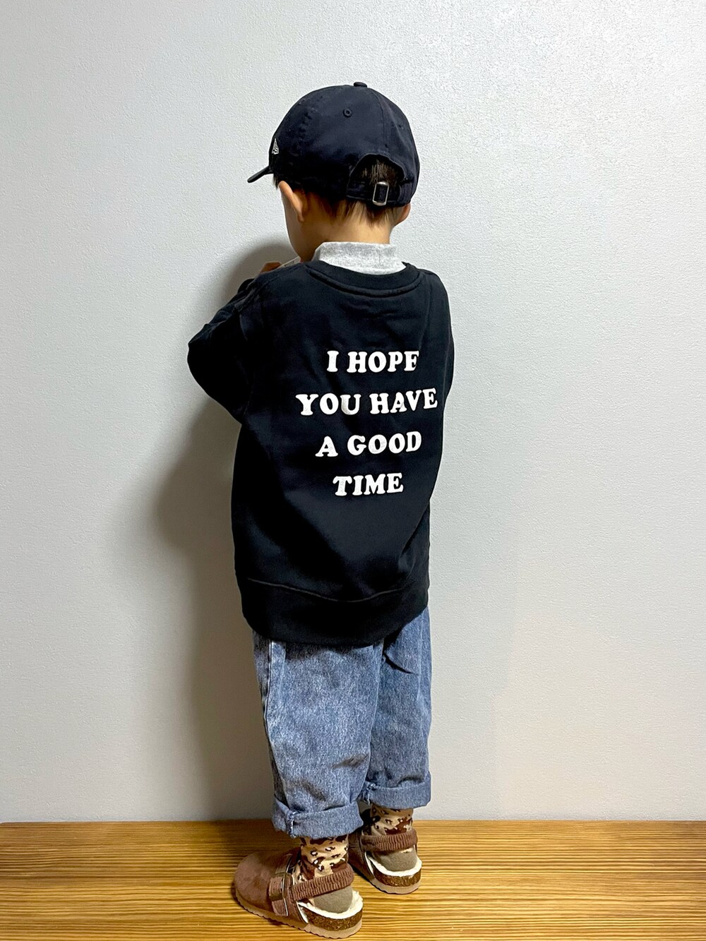 ブルー系のデニムパンツ、ブラック系のスウェット、ブラウン系のサンダルを着用したキッズの秋コーディネートの2枚目の写真