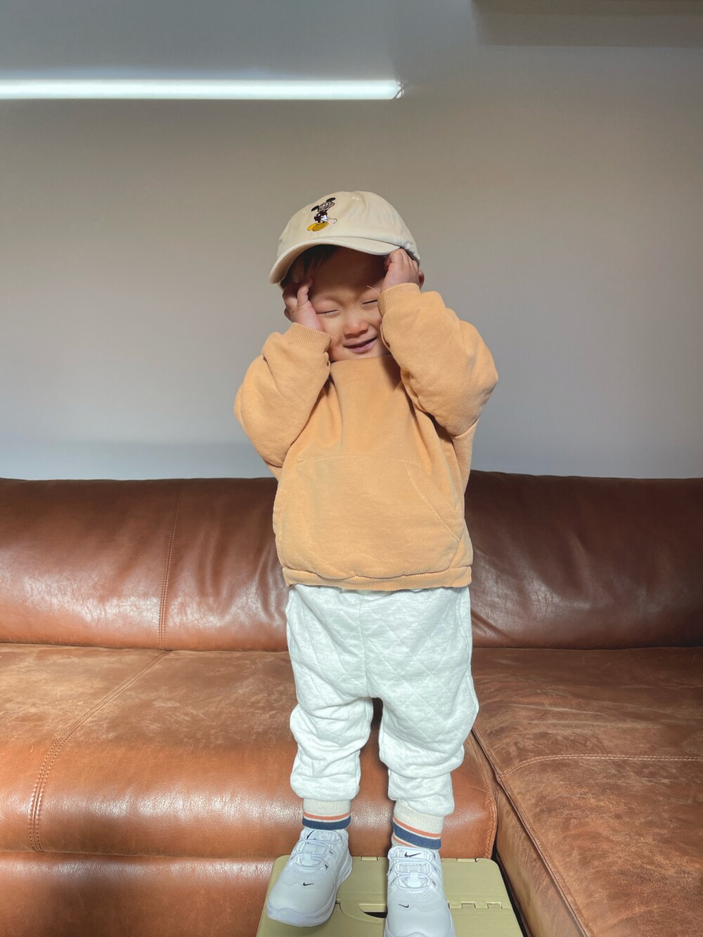 オレンジ系のスウェット、ホワイト系のその他パンツ、ベージュ系のキャップを着用したキッズの冬コーディネートの4枚目の写真