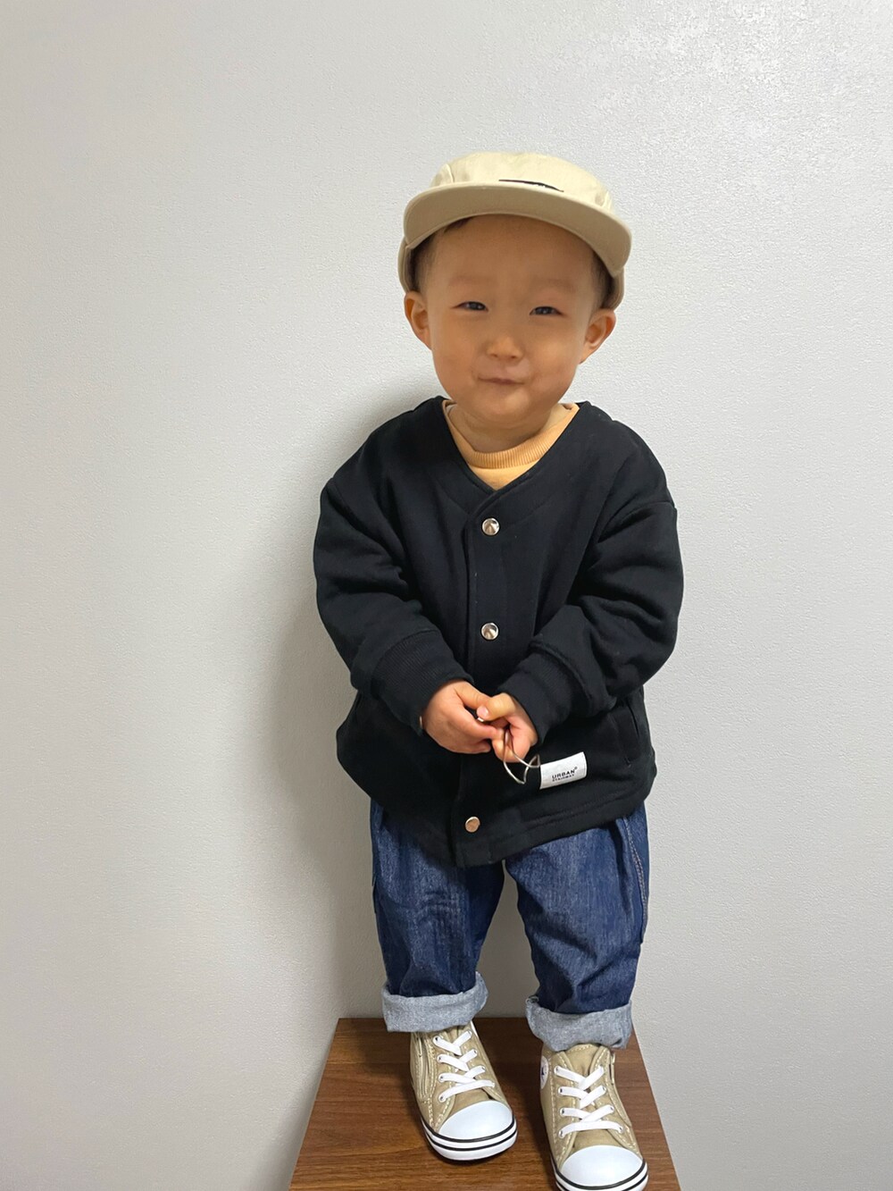 ブラック系のノーカラージャケット、オレンジ系のスウェット、その他のデニムパンツを着用したキッズの冬コーディネートの2枚目の写真