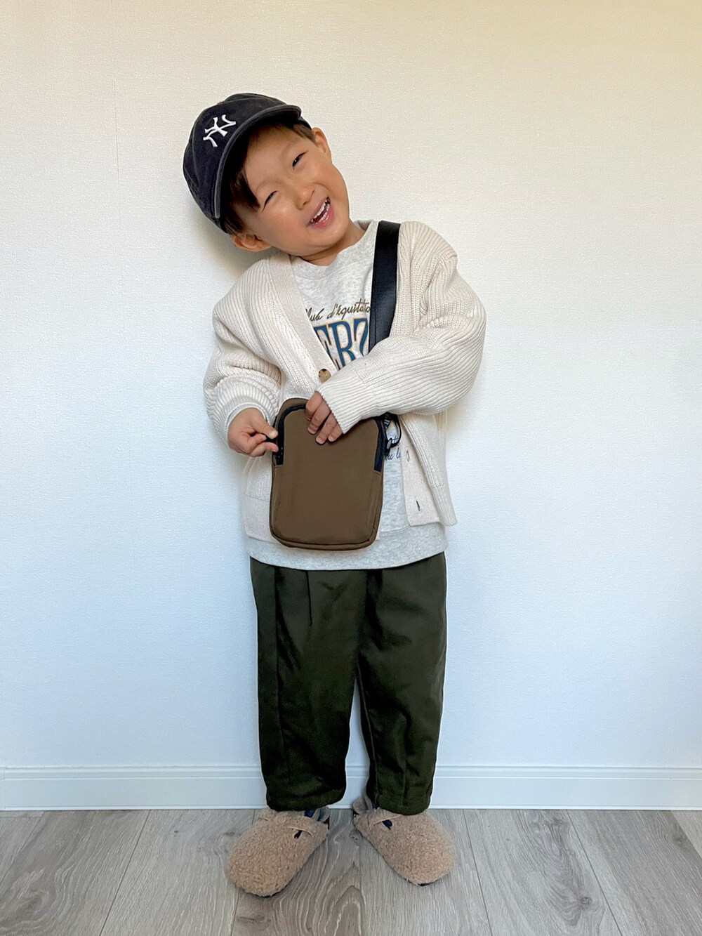グレー系のスウェット、ブラウン系のショルダーバッグ、ホワイト系のカーディガン/ボレロを着用したキッズの冬コーディネートの4枚目の写真