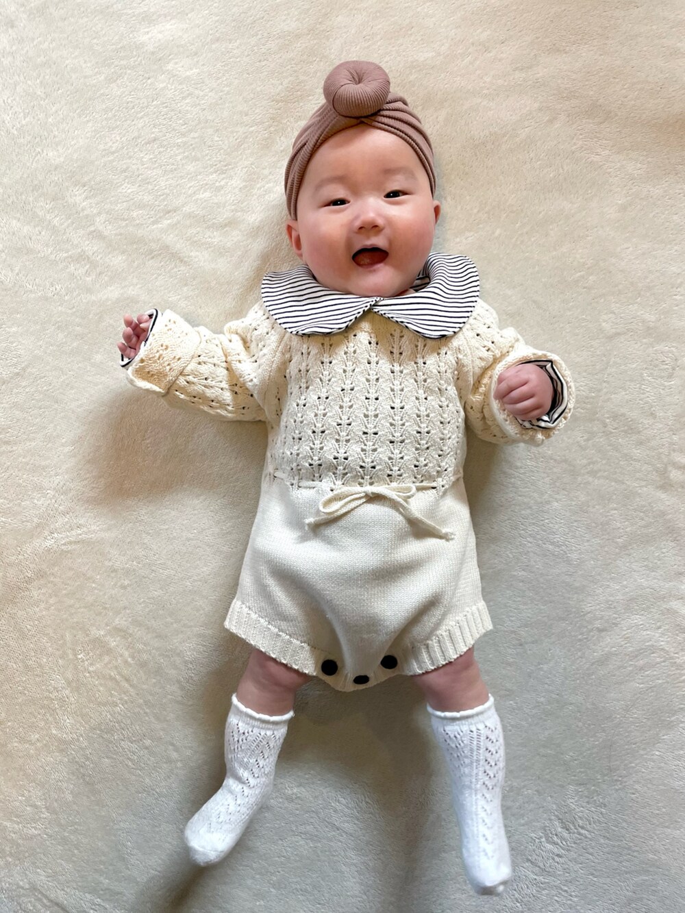 ブラウン系のヘアバンド、ブラック系のロンパース、ホワイト系のロンパースを着用したキッズの冬コーディネートの4枚目の写真