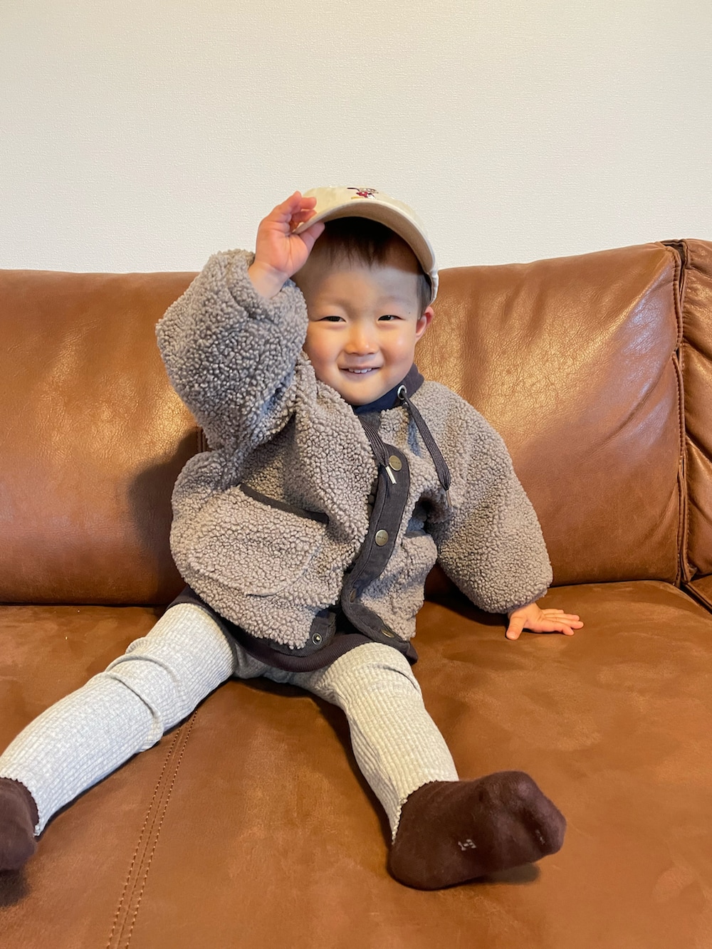 パープル系のパーカー、グレー系のノーカラージャケット、ベージュ系のキャップを着用したキッズの冬コーディネートの5枚目の写真