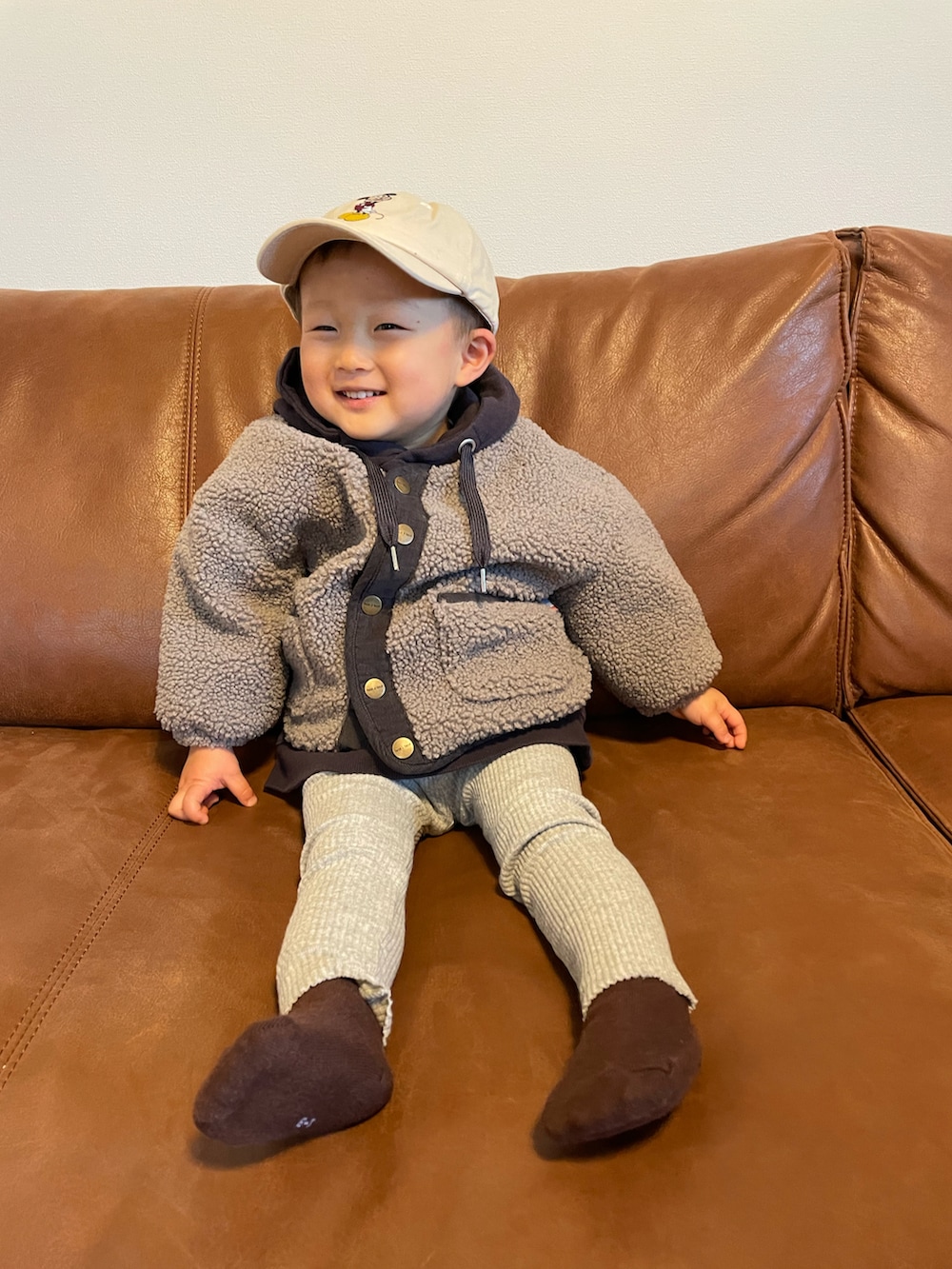 パープル系のパーカー、グレー系のノーカラージャケット、ベージュ系のキャップを着用したキッズの冬コーディネートの4枚目の写真