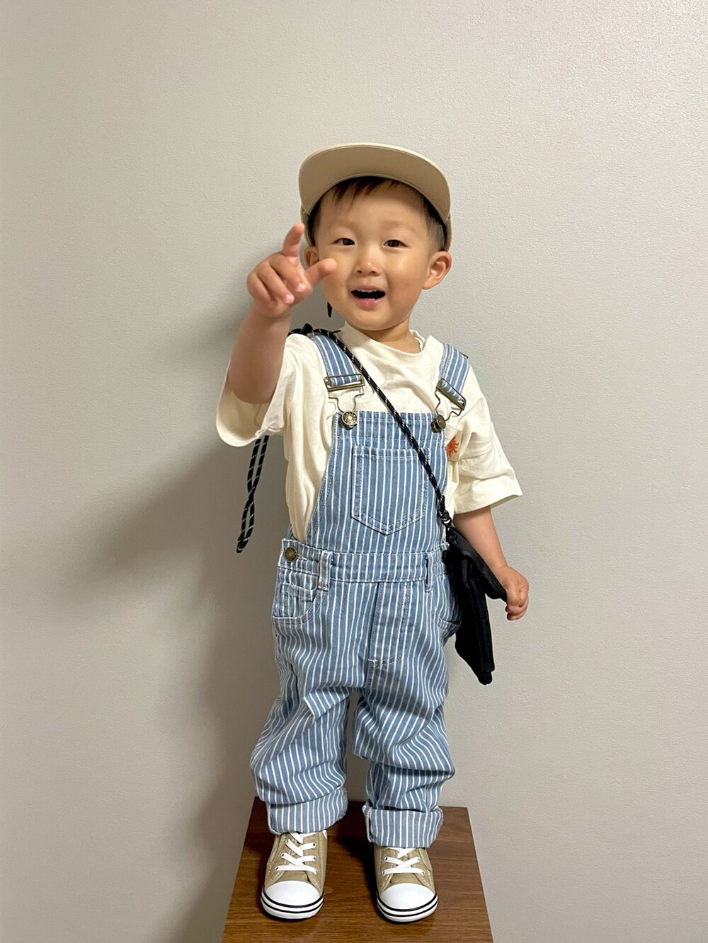 ブラック系のショルダーバッグ、ホワイト系のTシャツ/カットソー、ブルー系のサロペット/オーバーオールを着用したキッズの春コーディネートの3枚目の写真