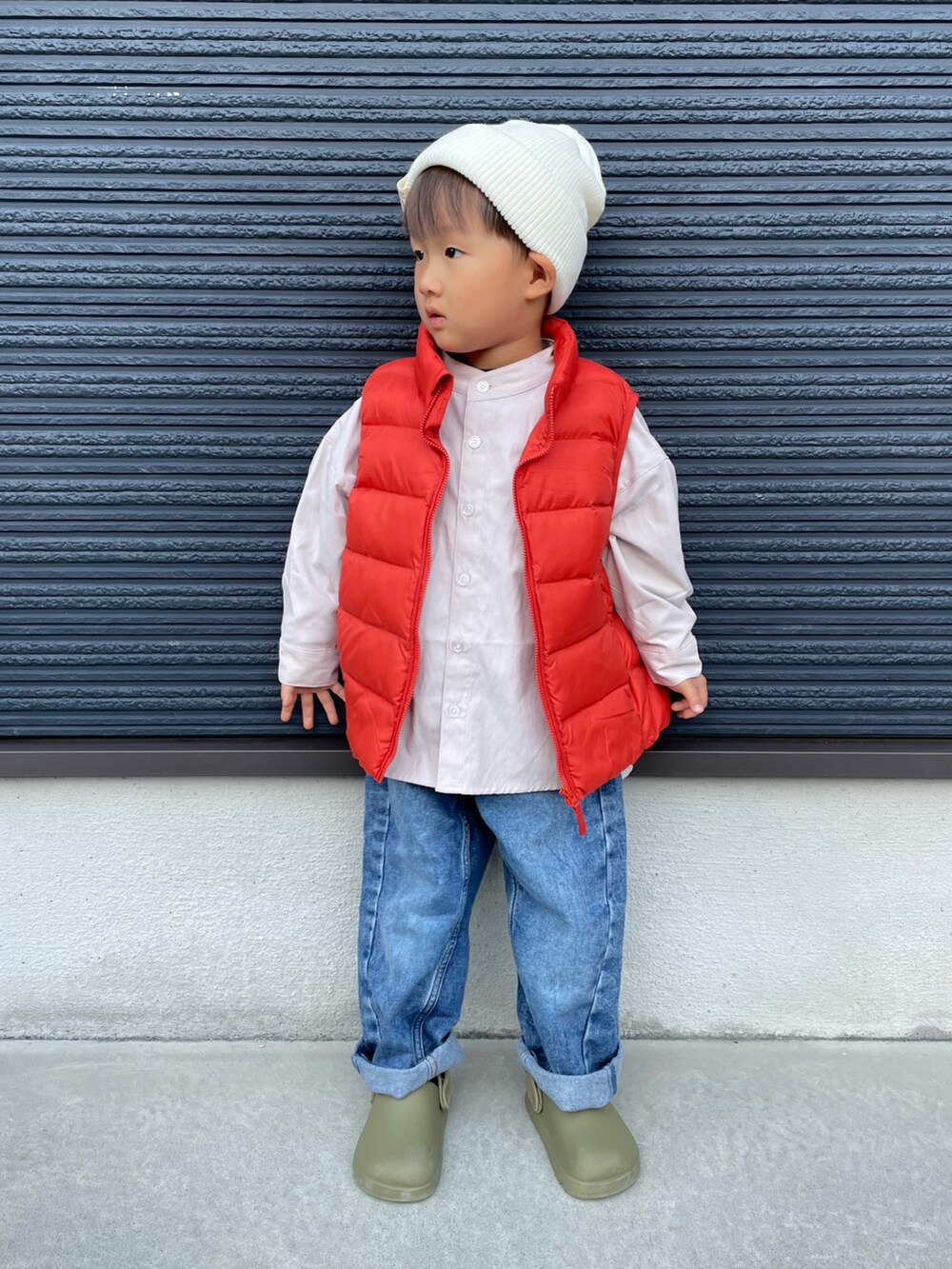 ベージュ系のシャツ/ブラウス、オレンジ系のダウンベスト、ブルー系のデニムパンツを着用したキッズの秋コーディネートの4枚目の写真