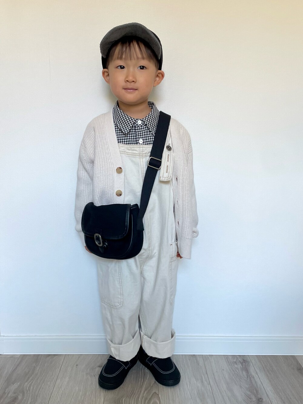 ブラック系のシャツ/ブラウス、ブラック系のショルダーバッグ、ホワイト系のカーディガン/ボレロを着用したキッズの冬コーディネートの2枚目の写真