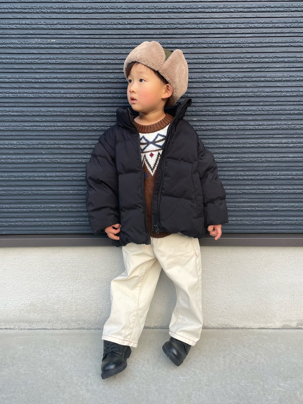 ブラウン系のニット/セーター、ブラック系のブルゾン、ホワイト系のデニムパンツを着用したキッズの冬コーディネートの3枚目の写真
