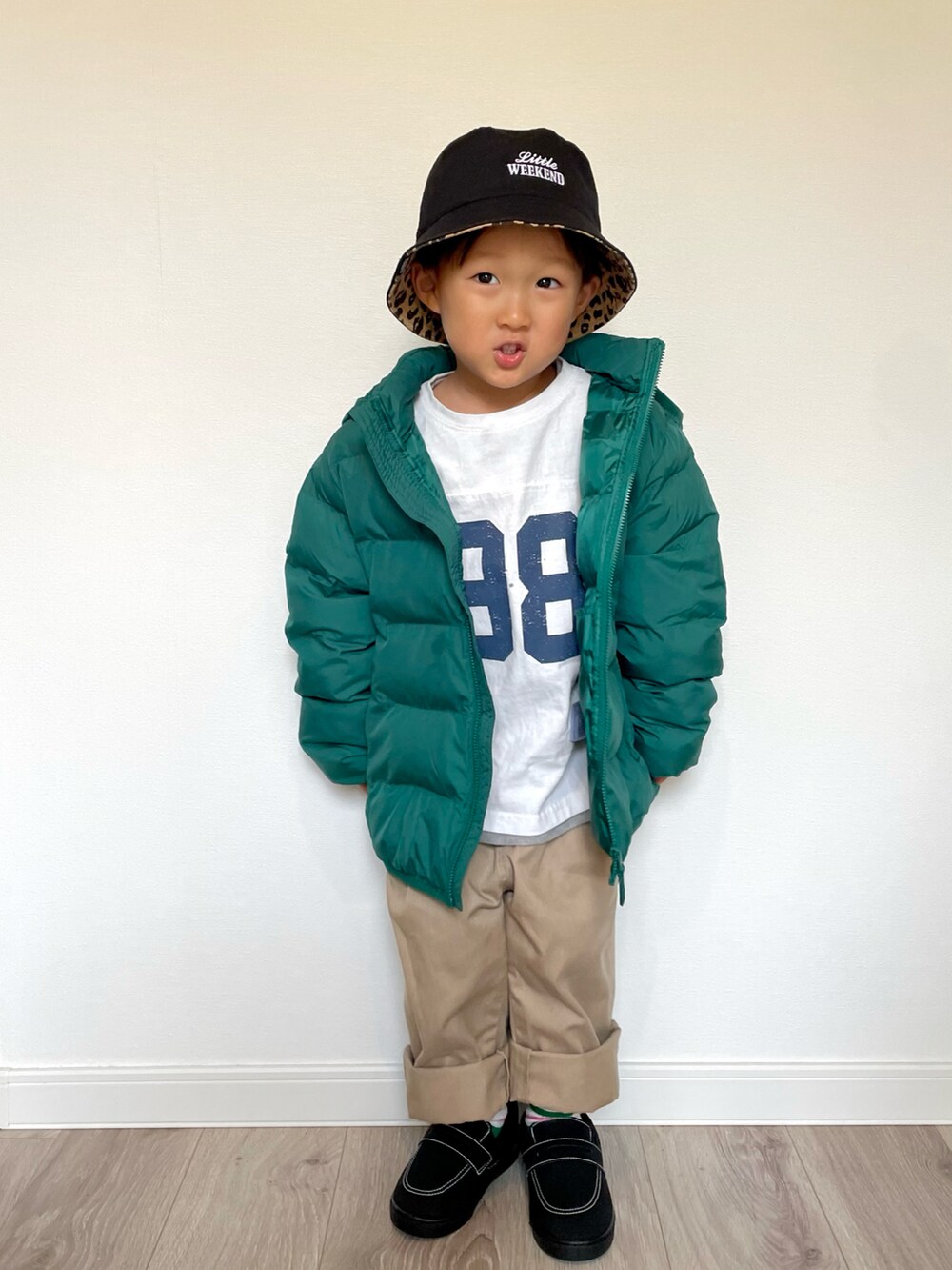 ホワイト系のTシャツ/カットソー、グリーン系のダウンジャケット/コート、ベージュ系のチノパンツを着用したキッズの冬コーディネートの2枚目の写真