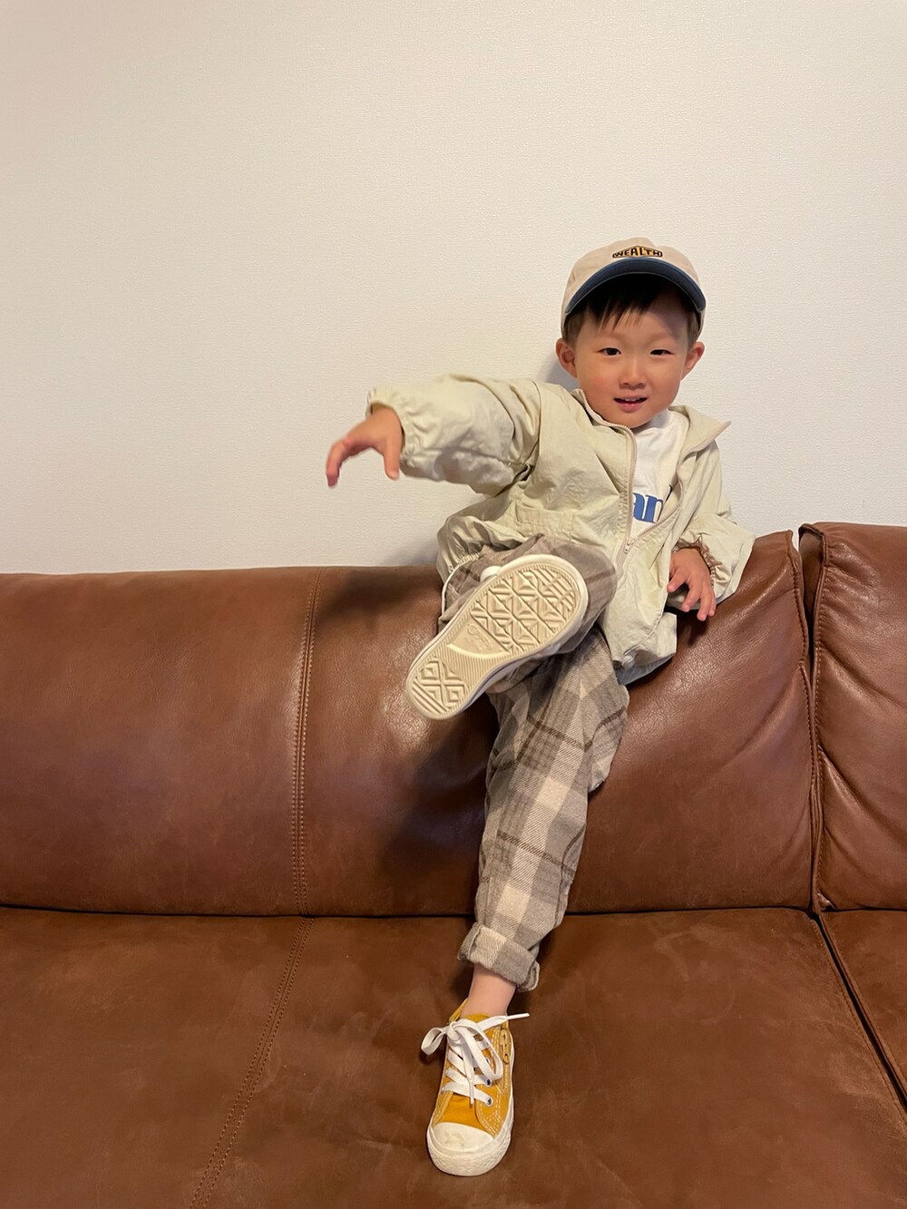 ベージュ系のナイロンジャケット、ホワイト系のTシャツ/カットソー、イエロー系のスニーカーを着用したキッズの春コーディネートの4枚目の写真