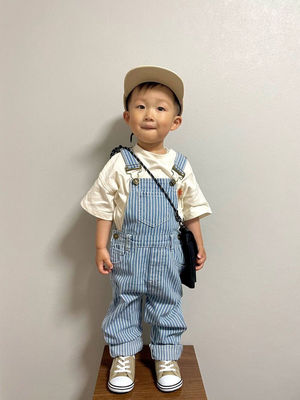 ブラック系のショルダーバッグ、ホワイト系のTシャツ/カットソー、ブルー系のサロペット/オーバーオールを着用したキッズの春コーディネートの4枚目の写真