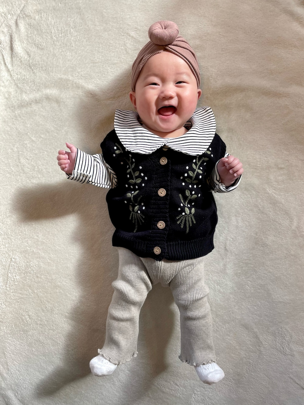 ブラック系のベスト、ベージュ系のセットアップ、ブラウン系のヘアバンドを着用したキッズの冬コーディネートの2枚目の写真