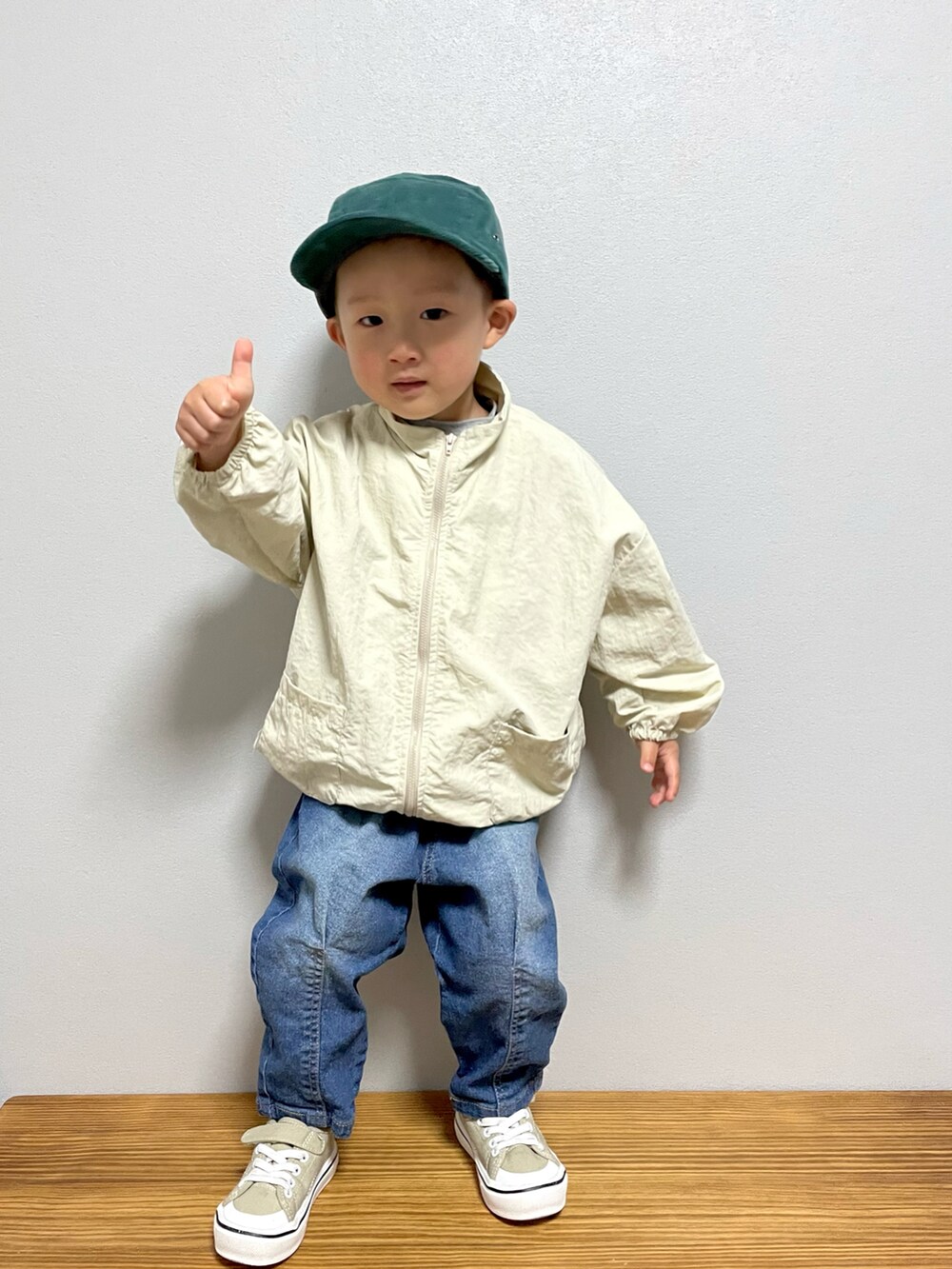 ベージュ系のナイロンジャケット、ホワイト系のTシャツ/カットソー、ブルー系のデニムパンツを着用したキッズの春コーディネートの4枚目の写真