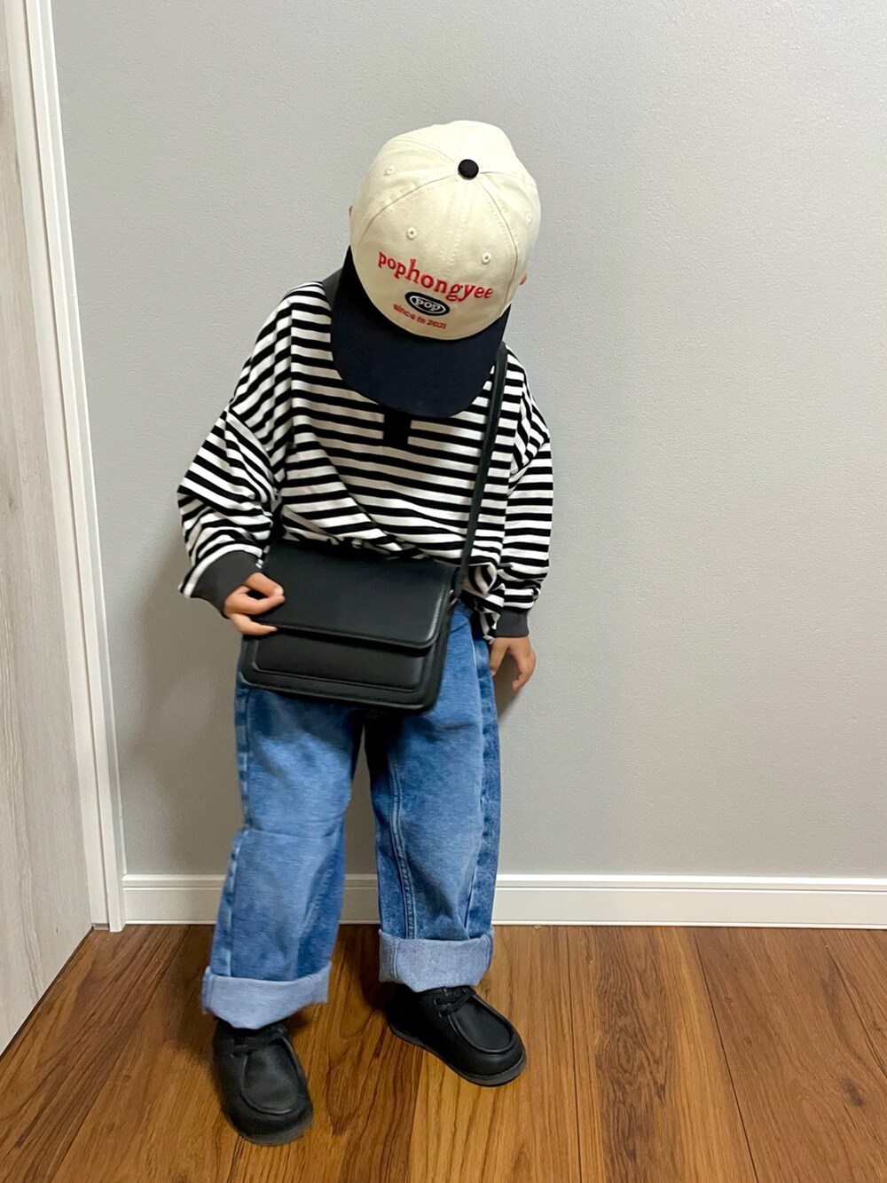 ブラック系のTシャツ/カットソー、ブラック系のショルダーバッグ、ブルー系のデニムパンツを着用したキッズの秋コーディネートの2枚目の写真