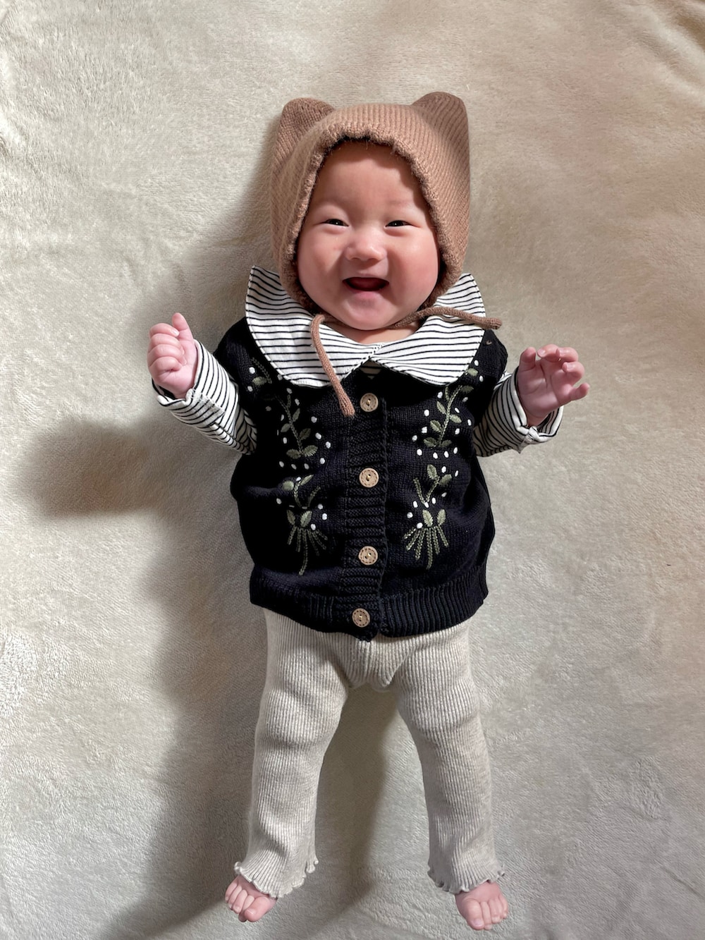 ブラック系のベスト、ベージュ系のセットアップ、ブラウン系のヘアバンドを着用したキッズの冬コーディネートの4枚目の写真