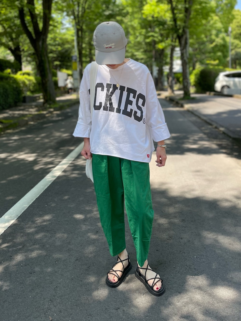ホワイト系のTシャツ/カットソー、ブラック系のサンダル、グリーン系のチノパンツを着用したレディースの夏コーディネートの2枚目の写真