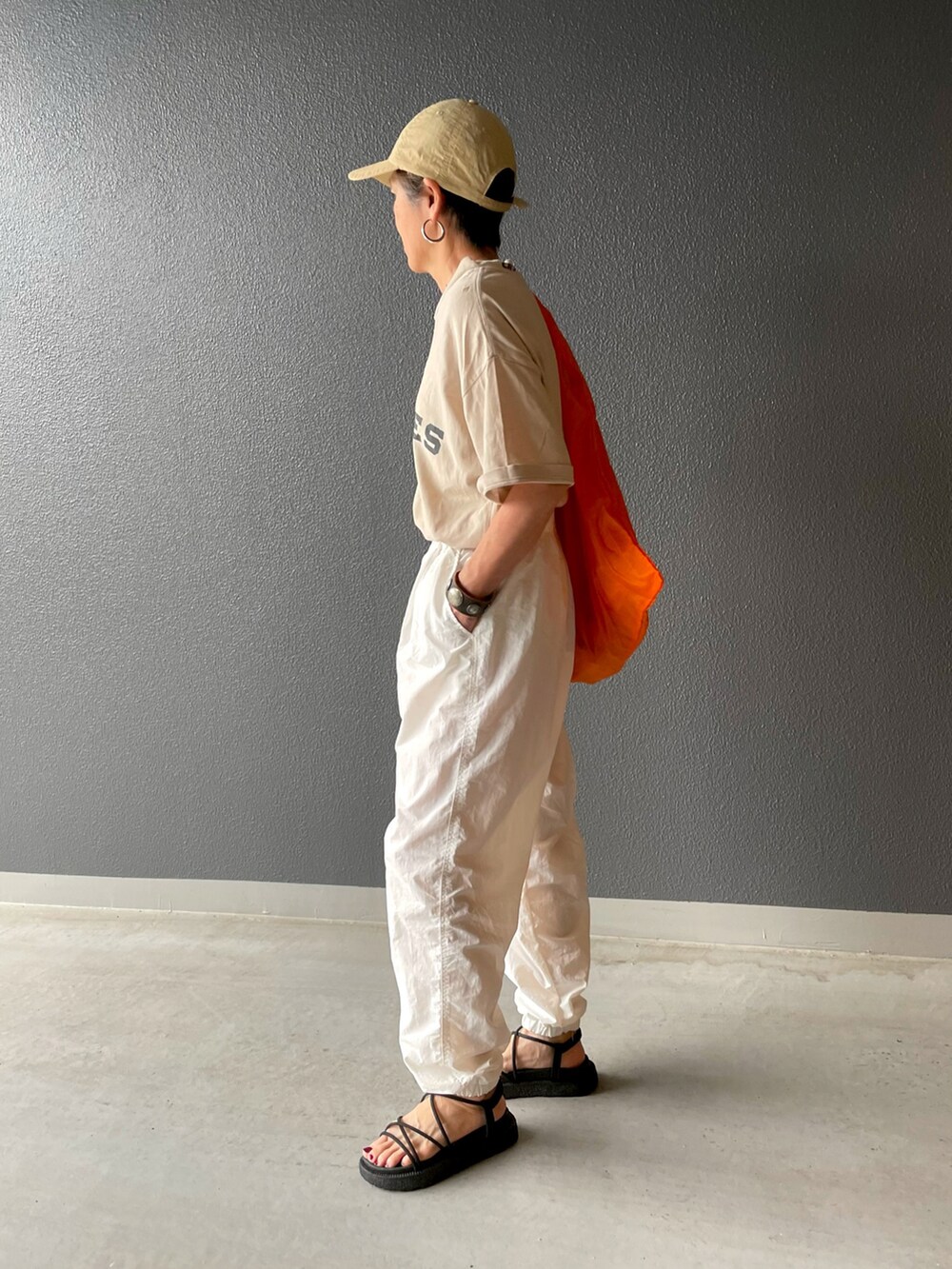 ホワイト系のその他パンツ、ブラック系のサンダル、オレンジ系のハンドバッグを着用したレディースの夏コーディネートの2枚目の写真