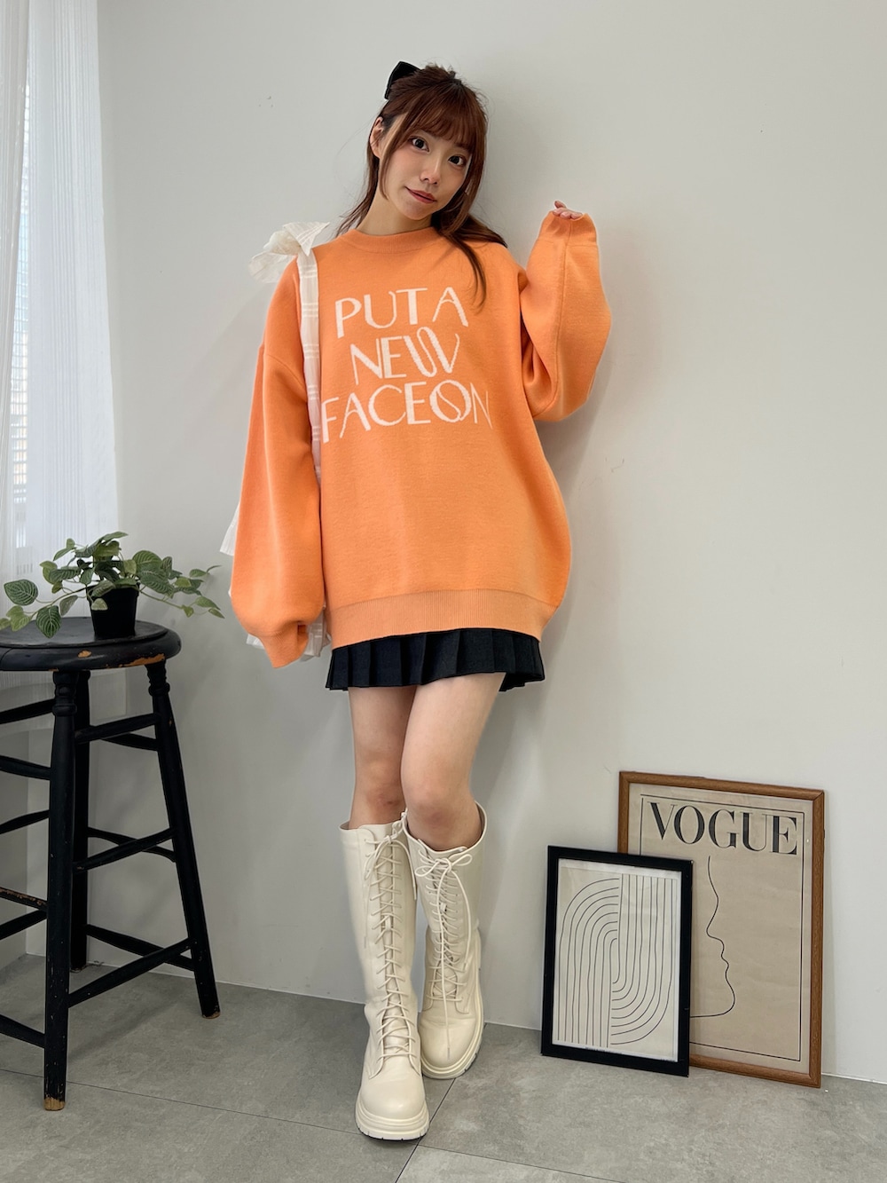 オレンジ系のニット/セーター、ブラック系のスカート、ホワイト系のブーツを着用したレディースの冬コーディネートの2枚目の写真