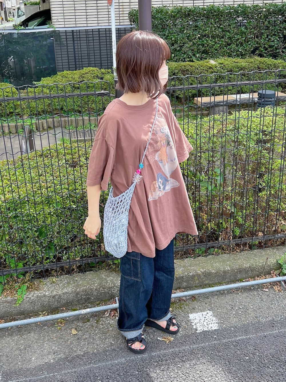 ブラウン系のTシャツ/カットソー、ブルー系のデニムパンツ、ブラック系のサンダルを着用したレディースの秋コーディネートの2枚目の写真