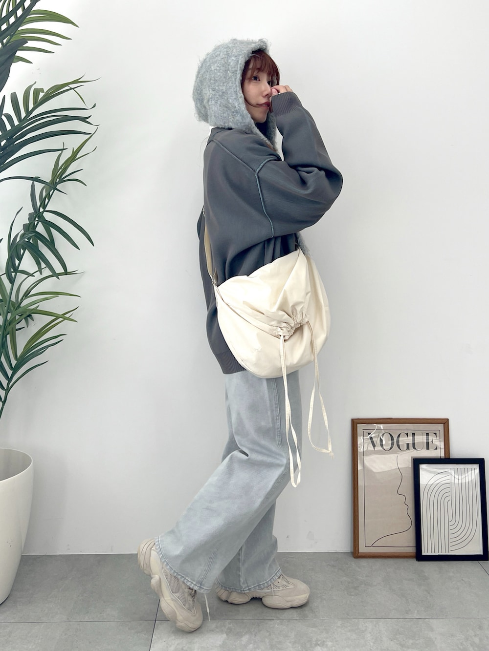 グレー系のカーディガン/ボレロ、グレー系のデニムパンツ、ホワイト系のショルダーバッグを着用したレディースの冬コーディネートの4枚目の写真